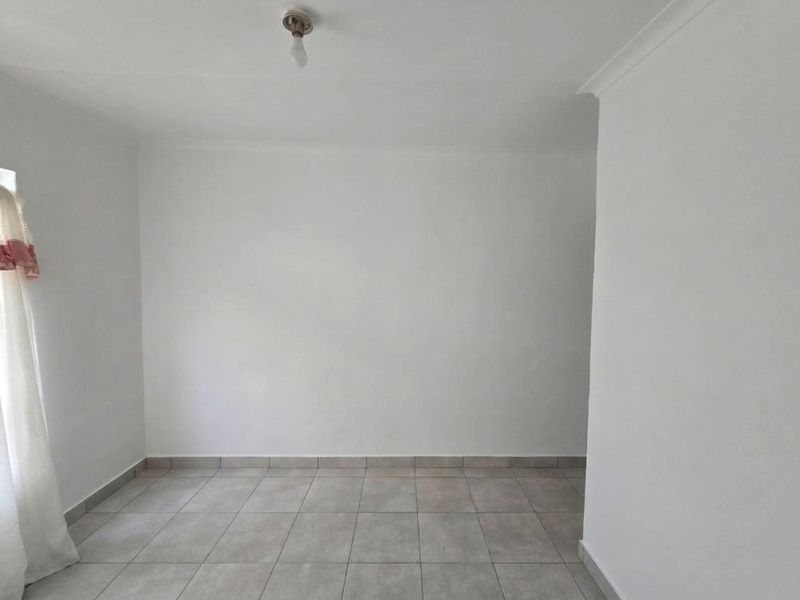 A clean, empty bedroom featuring neutral tiled flooring and simple white walls, providing a blank canvas for interior design.