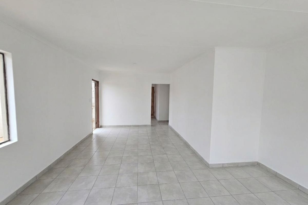 A bright, spacious, and empty living area featuring neutral tiled flooring and clean white walls, ready for personalization.