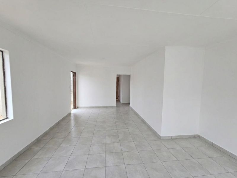 A bright, spacious, and empty living area featuring neutral tiled flooring and clean white walls, ready for personalization.