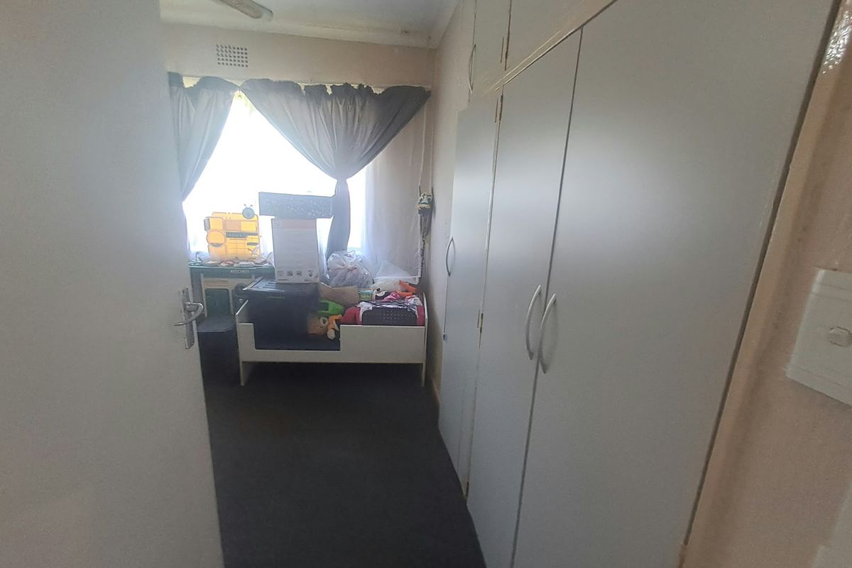 A bedroom featuring built-in cupboards, a ceiling fan, and a window, requiring cosmetic updates to improve its overall condition.