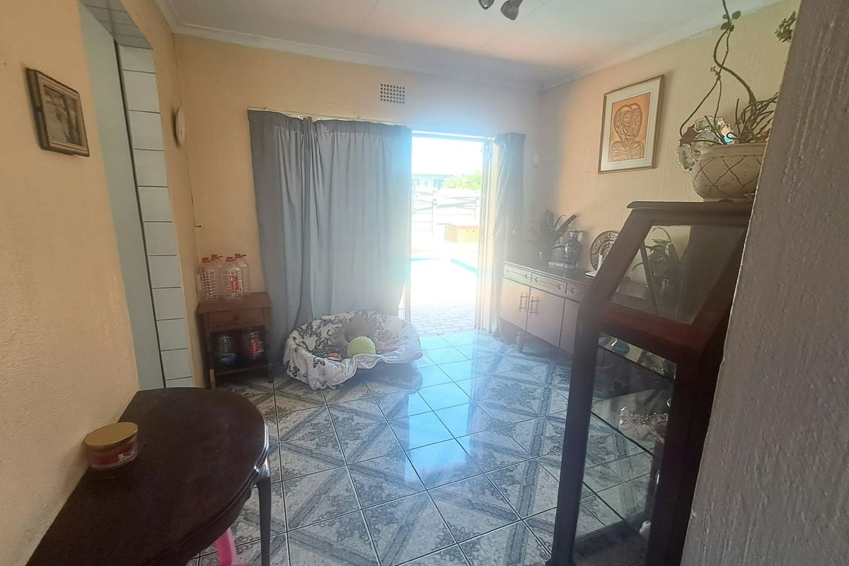 A living area featuring tiled flooring and a sliding glass door providing access to the outdoor pool area.