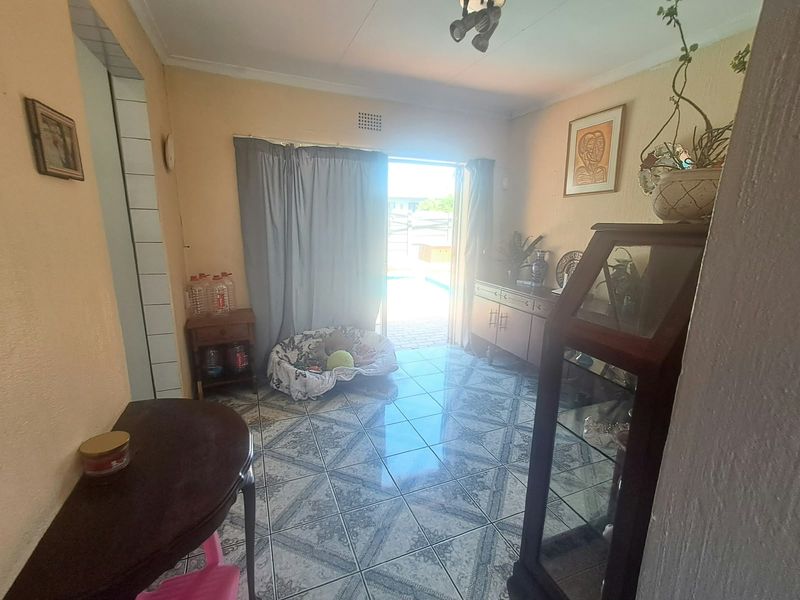 A living area featuring tiled flooring and a sliding glass door providing access to the outdoor pool area.