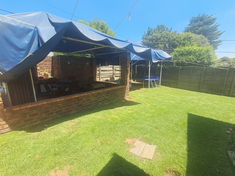 Outdoor entertainment area featuring a brick-built covered patio structure overlooking a private garden with perimeter fencing.
