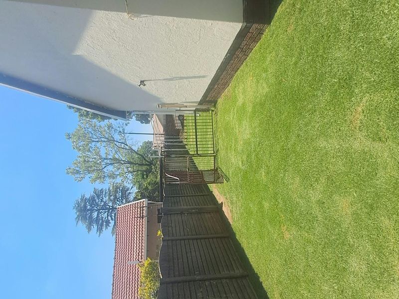 A side garden area featuring a well-maintained lawn, enclosed by a timber fence and a metal gate.