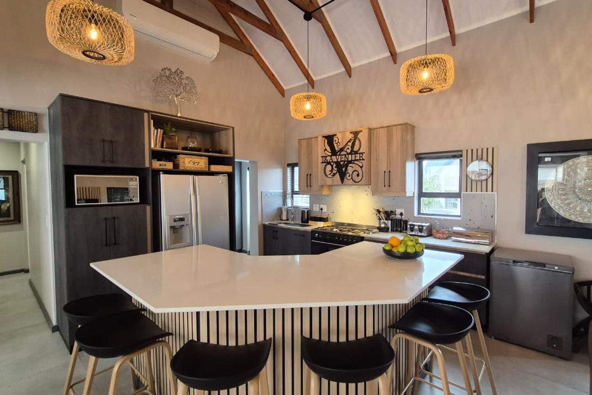Modern kitchen featuring stone countertops, built-in cabinetry, gas hob, and high vaulted ceilings with exposed timber rafters.