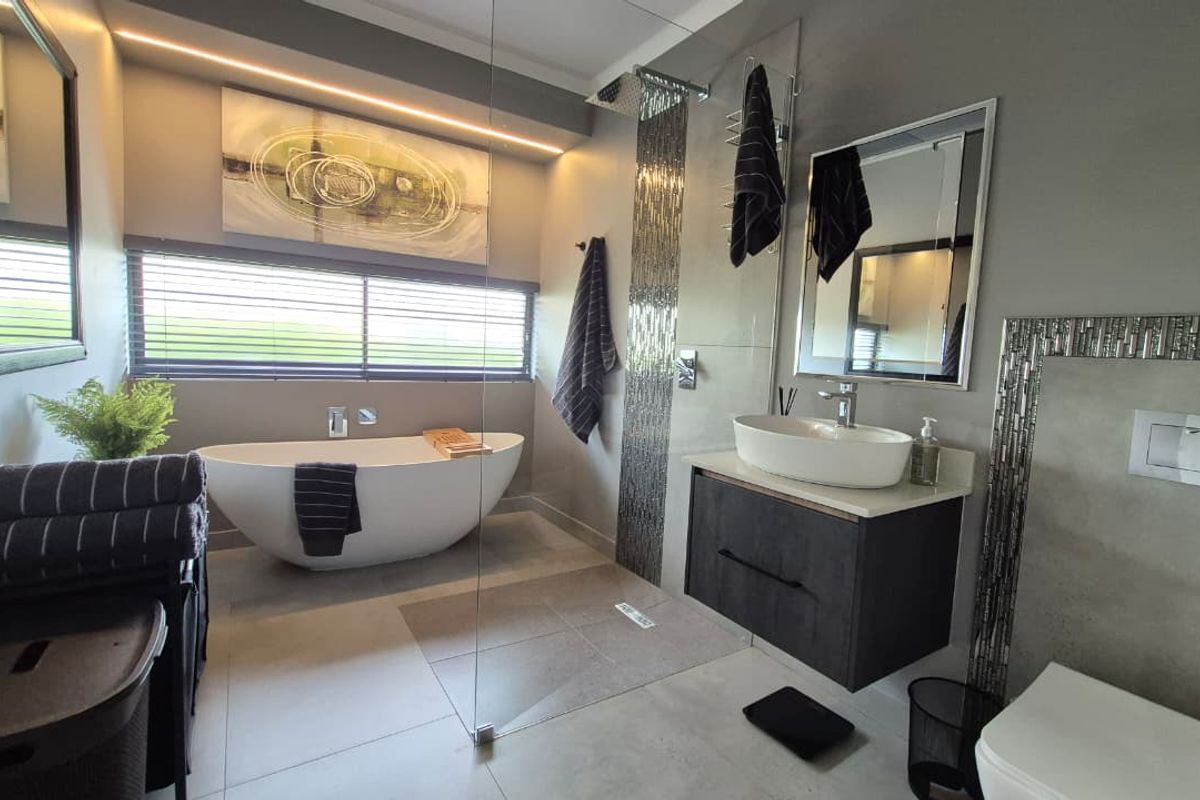 Modern, high-end bathroom featuring a sleek freestanding bathtub, walk-in shower with mosaic accents, wall-mounted vanity with vessel sink, and a concealed cistern toilet.