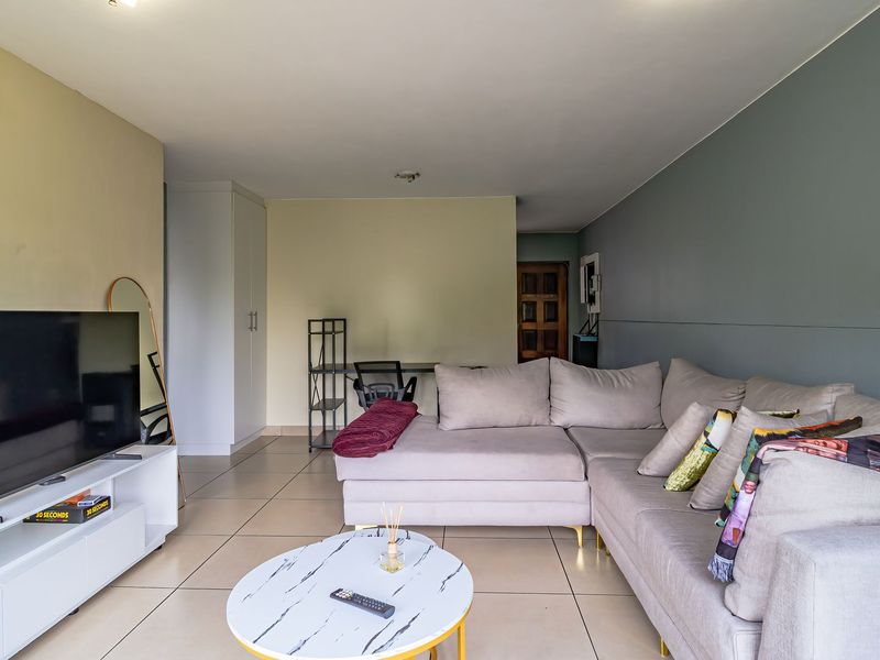 A spacious living room featuring neutral tiled flooring and a built-in storage cupboard, offering a functional and versatile layout.