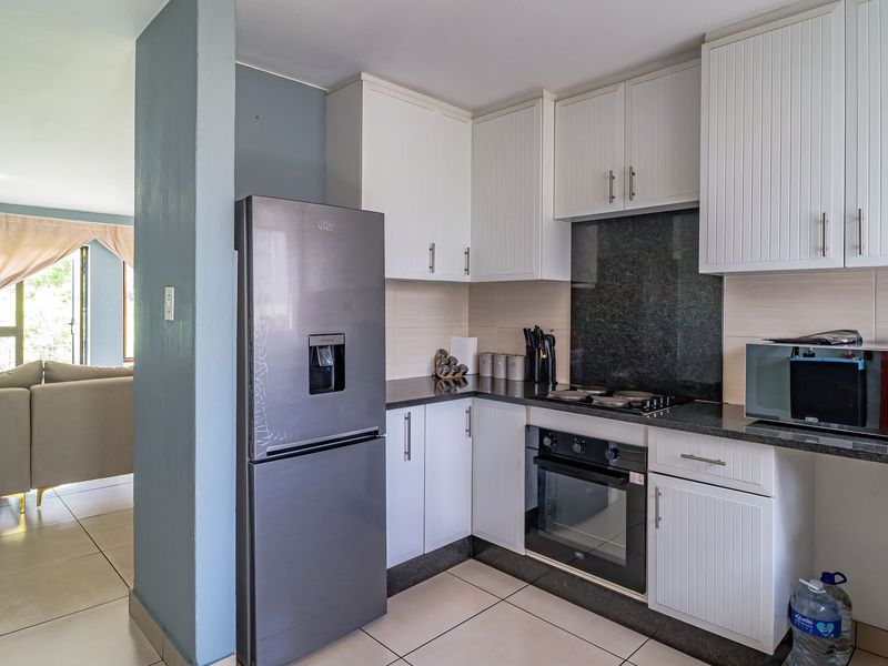Open-plan kitchen featuring white cabinetry, granite countertops, and integrated appliances, seamlessly flowing into the adjacent living area.