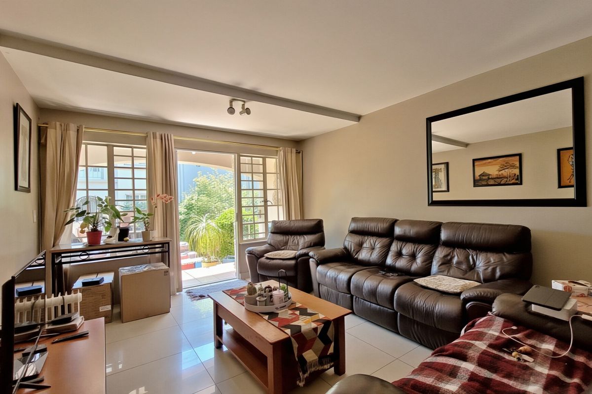 A bright living room featuring tiled flooring and a sliding glass door that provides direct access to the outdoor patio area.