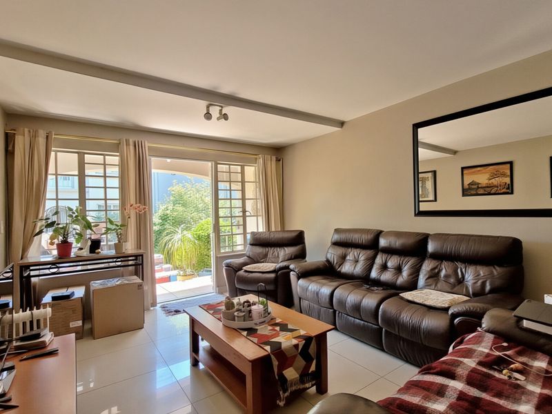 A bright living room featuring tiled flooring and a sliding glass door that provides direct access to the outdoor patio area.