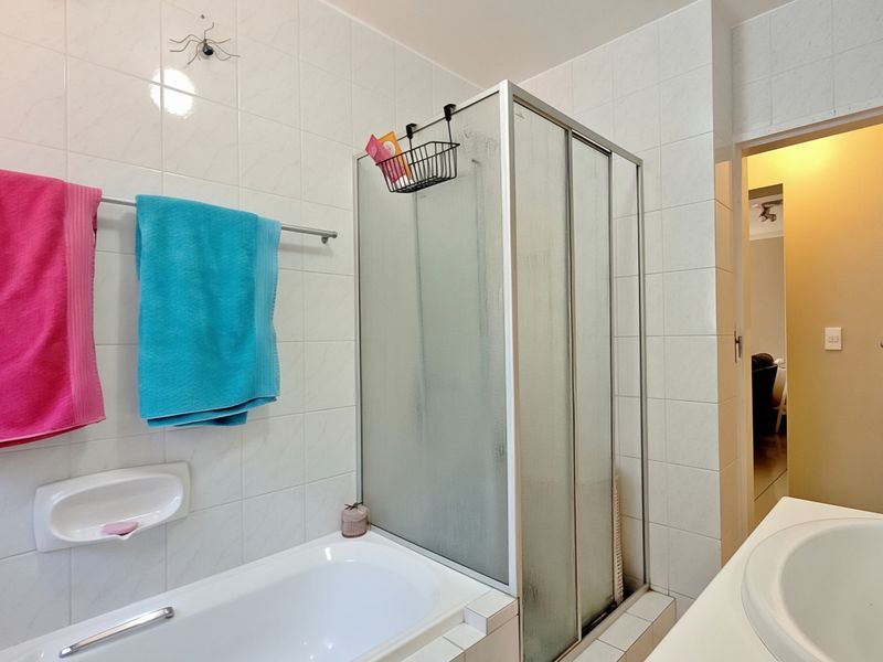 A functional bathroom featuring a built-in bathtub, a separate shower enclosure, and a vanity basin with tiled wall finishes.