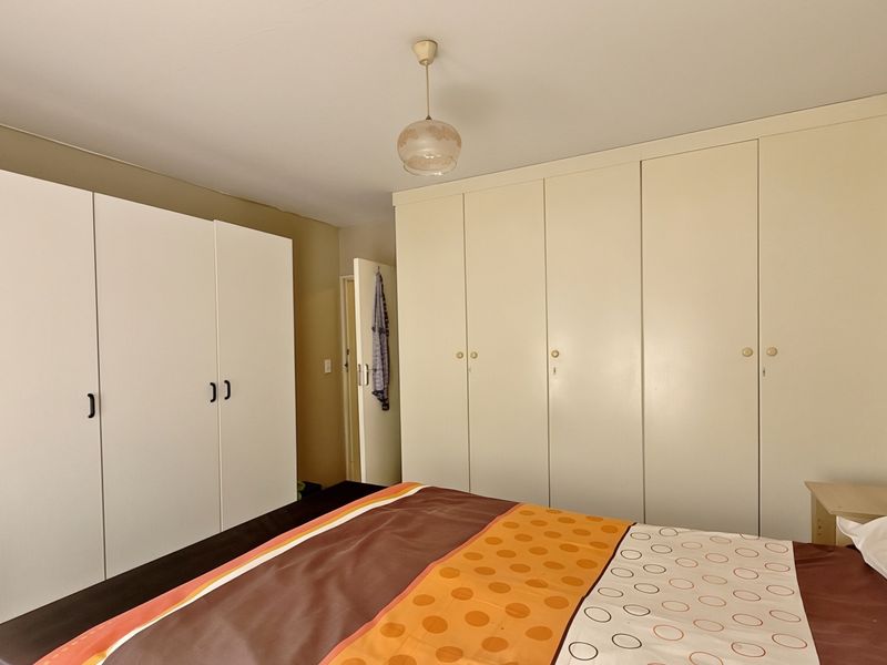 A bedroom featuring extensive built-in cupboard storage and a central pendant light fixture.