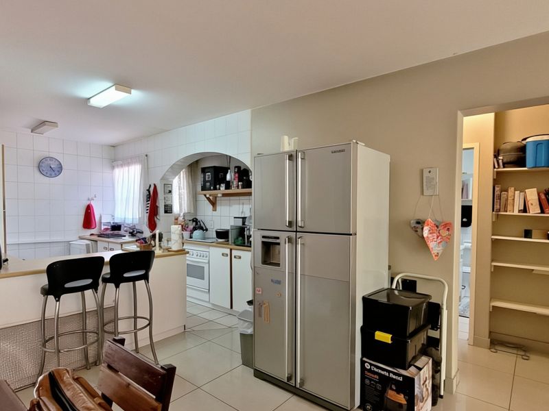 Open plan kitchen area featuring tiled flooring, built-in cabinetry, a breakfast counter, and an adjacent walk-in pantry or storage space.