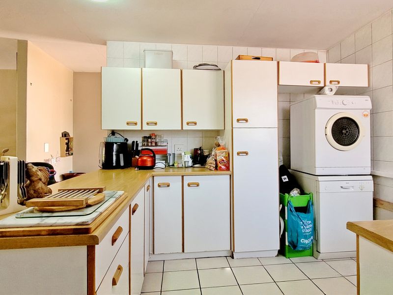A functional kitchen featuring laminate countertops, tiled backsplash, and integrated cabinetry with dedicated space for laundry appliances.
