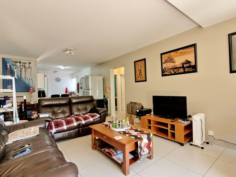 Open plan living area featuring tiled flooring and a connected kitchen space, providing a functional layout for daily living.