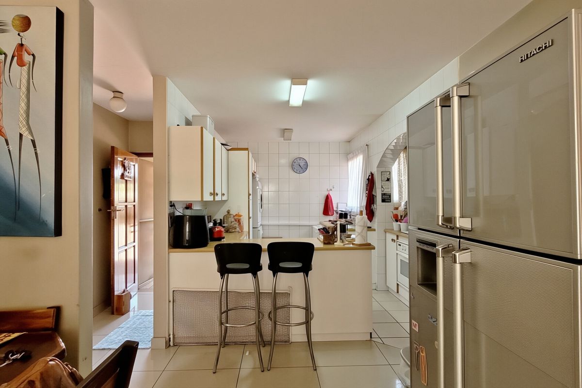 A functional kitchen featuring tiled flooring, a breakfast counter, and built-in cabinetry with a classic tiled backsplash.