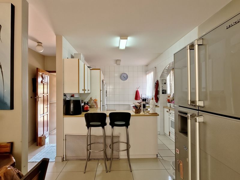 A functional kitchen featuring tiled flooring, a breakfast counter, and built-in cabinetry with a classic tiled backsplash.
