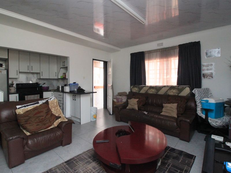 Open plan living area featuring tiled flooring and an integrated kitchen with built-in cabinetry, providing a functional layout for daily living.