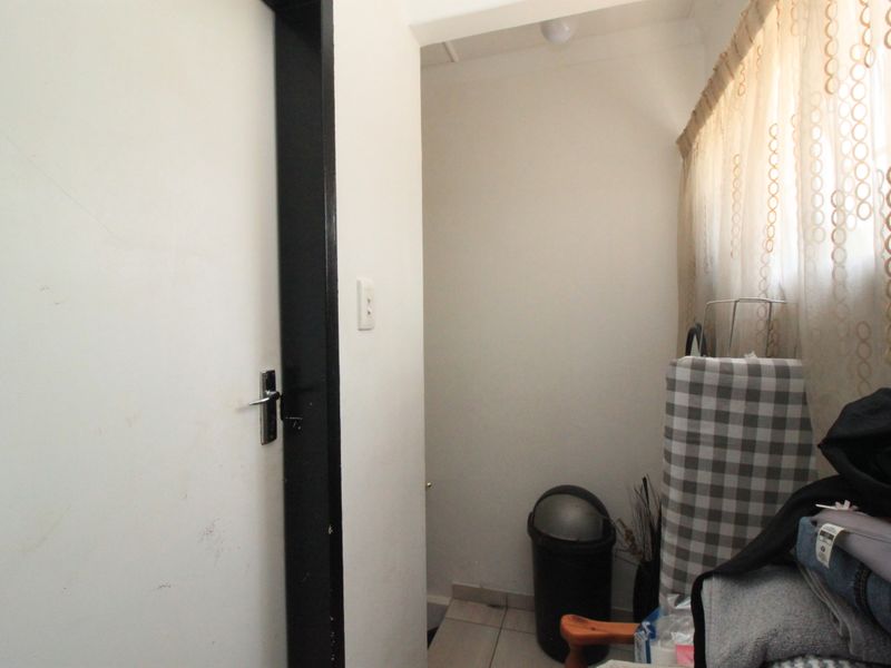 A small laundry or utility area featuring tiled flooring and a doorway, providing a functional space for household tasks.