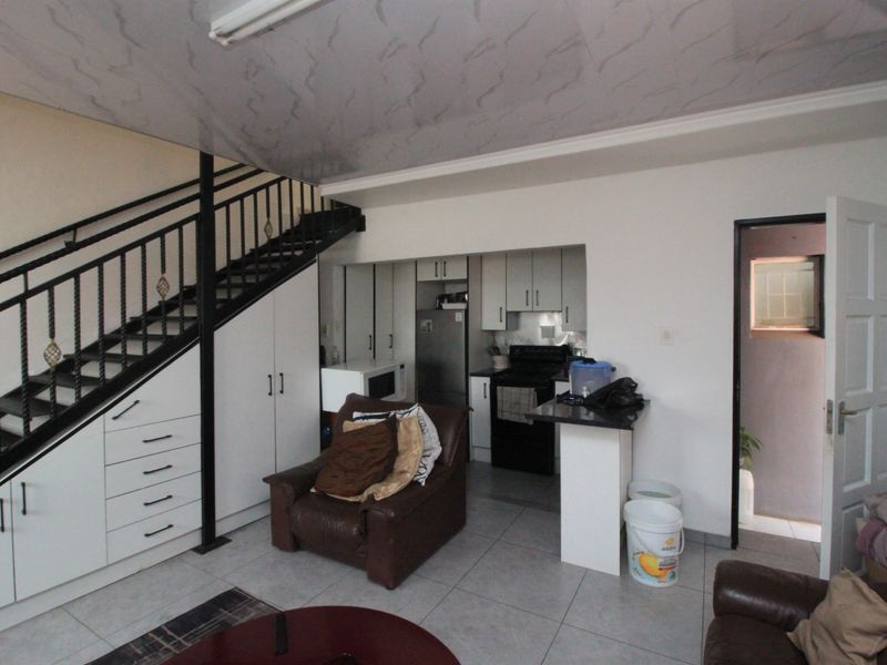 Open plan living area featuring a kitchen with built-in cabinetry, a breakfast counter, and integrated storage under the staircase.