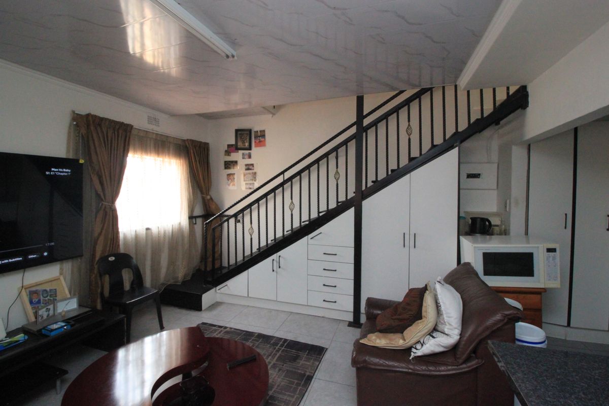 Open plan living area featuring a staircase with integrated under-stair storage cabinetry and tiled flooring.