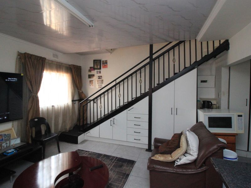 Open plan living area featuring a staircase with integrated under-stair storage cabinetry and tiled flooring.