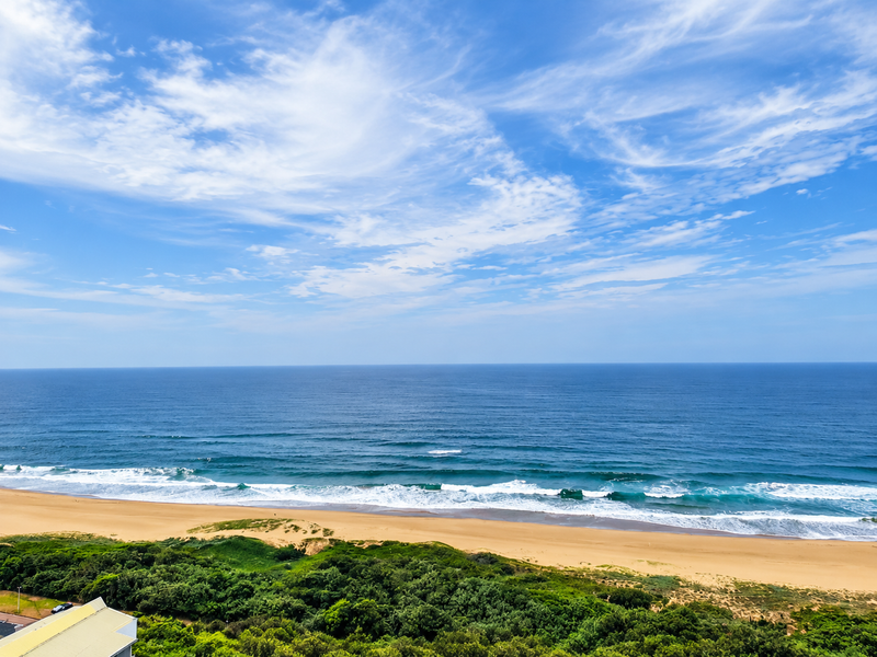 A scenic elevated view overlooking the coastline, sandy beach, and ocean horizon.
