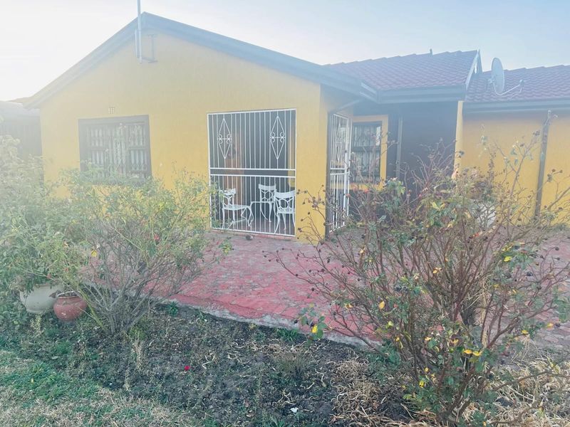 Rear view of the property featuring a paved patio area, security gates on windows and doors, and a tiled roof.