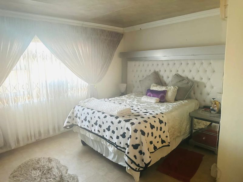 A bedroom featuring a built-in headboard, tiled flooring, and decorative ceiling cornice, offering a functional space with potential for cosmetic updates.