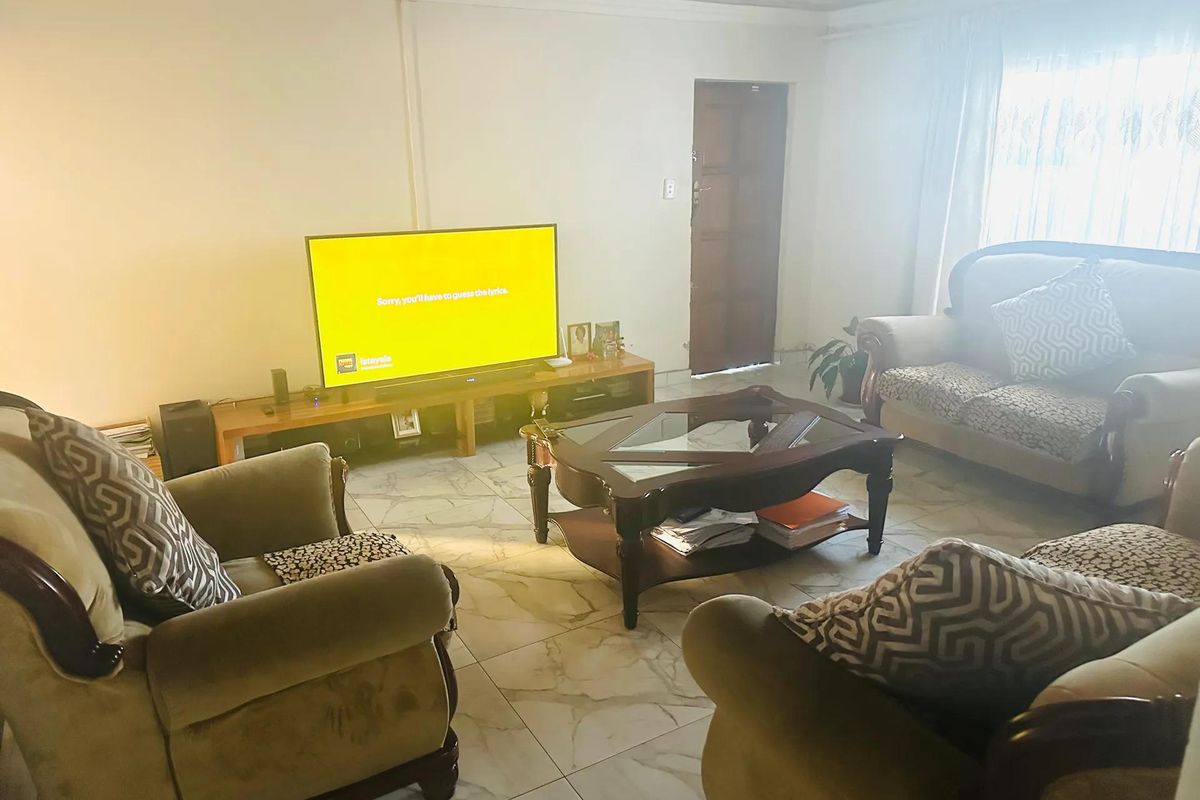 A living room featuring tiled flooring and a timber ceiling, providing a functional space with natural light from the window.