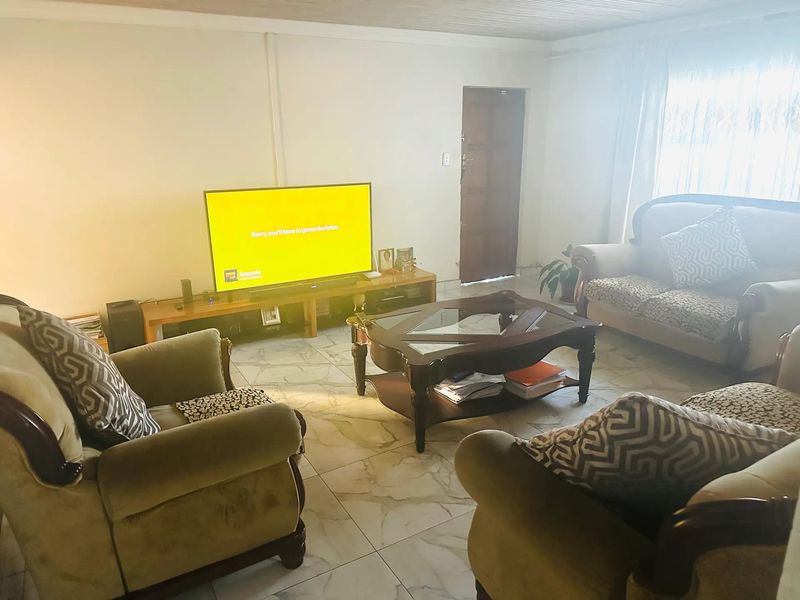 A living room featuring tiled flooring and a timber ceiling, providing a functional space with natural light from the window.