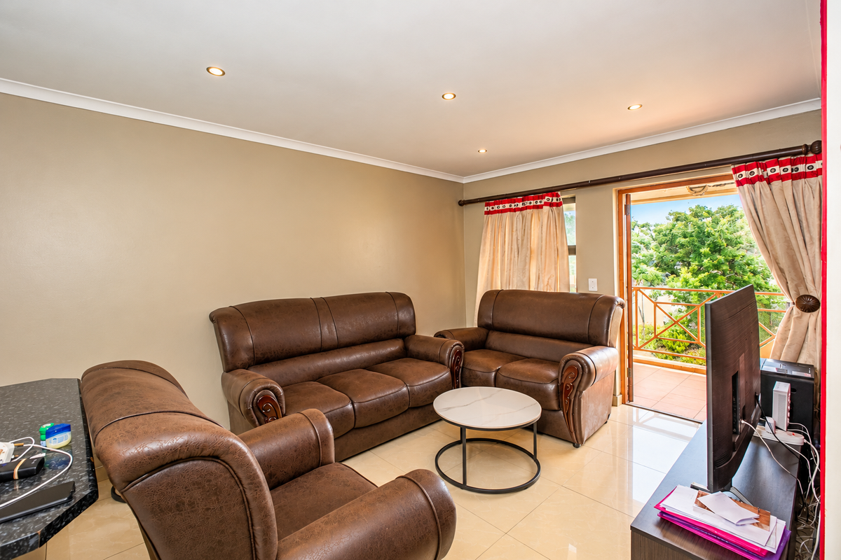 A living room featuring tiled flooring, recessed downlights, and a sliding glass door providing direct access to an outdoor balcony area.