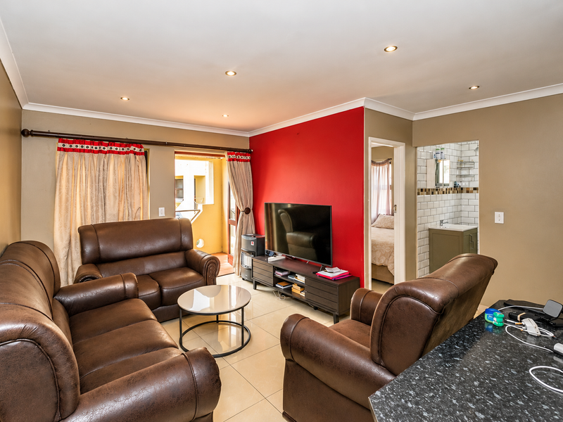 Open plan living area featuring tiled floors, recessed lighting, and a modern kitchen counter, with direct access to a balcony and adjacent bathroom.