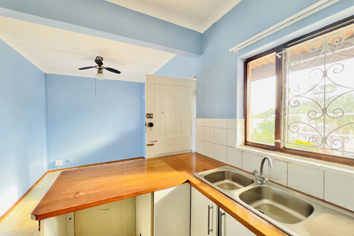 A functional kitchen area featuring a double bowl stainless steel sink, wooden countertops, and built-in cabinetry, offering a bright and open layout.
