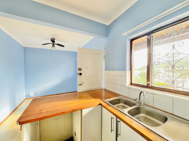 A functional kitchen area featuring a double bowl stainless steel sink, wooden countertops, and built-in cabinetry, offering a bright and open layout.