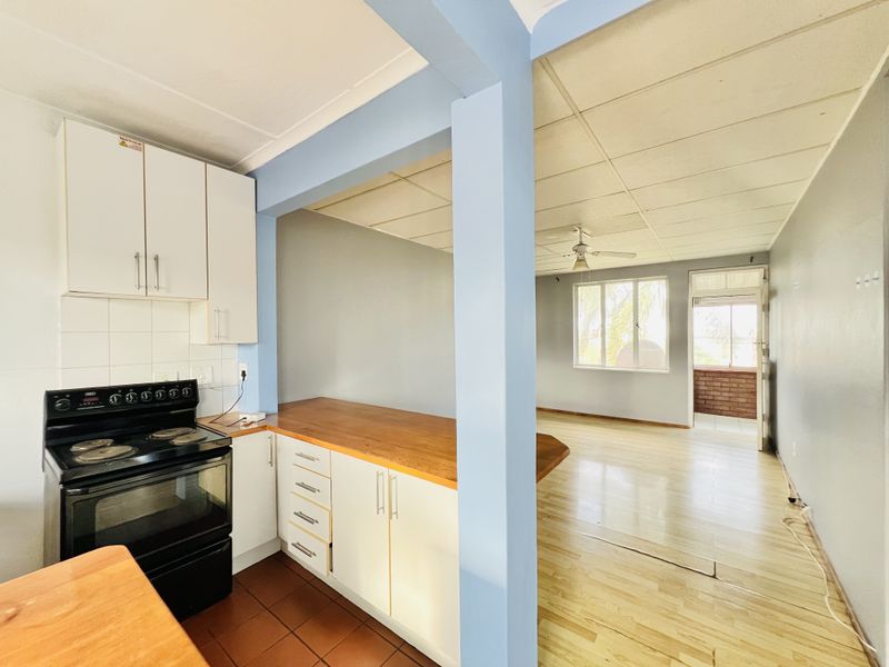 Open plan kitchen and living area featuring built-in cabinetry, wooden countertops, and a combination of tiled and laminate flooring.