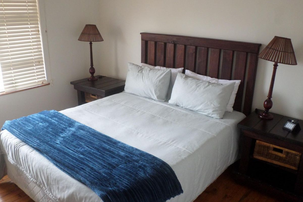 A cozy bedroom featuring warm timber flooring and fitted venetian blinds, providing a comfortable and functional sleeping space.
