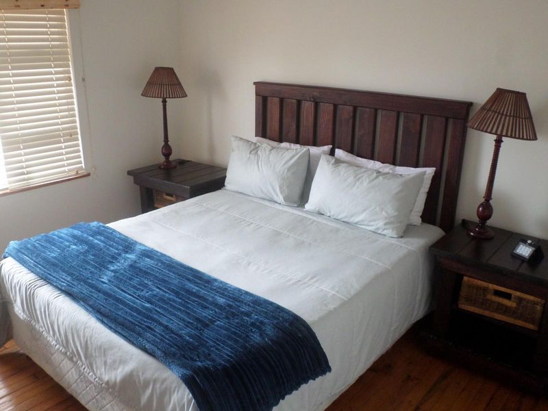 A cozy bedroom featuring warm timber flooring and fitted venetian blinds, providing a comfortable and functional sleeping space.