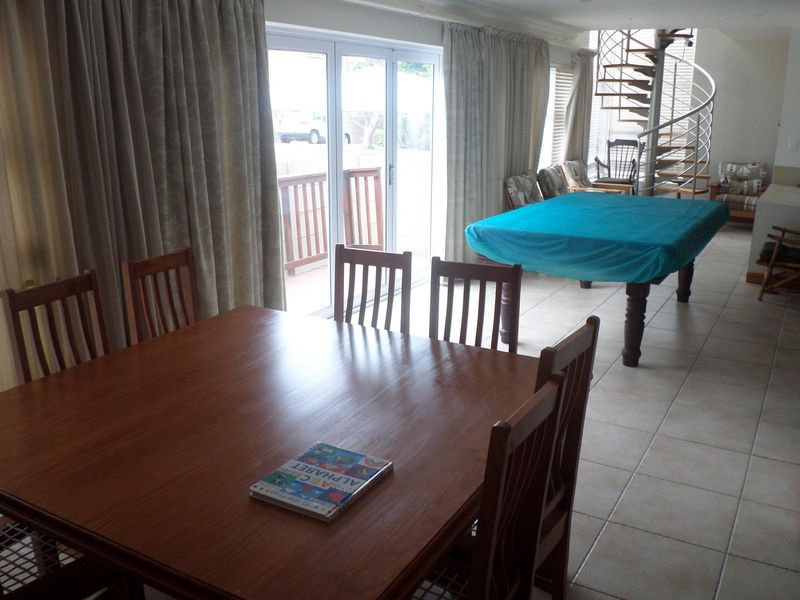 Spacious open-plan living and dining area featuring tiled flooring, a prominent spiral staircase, and large sliding glass doors leading to the exterior.