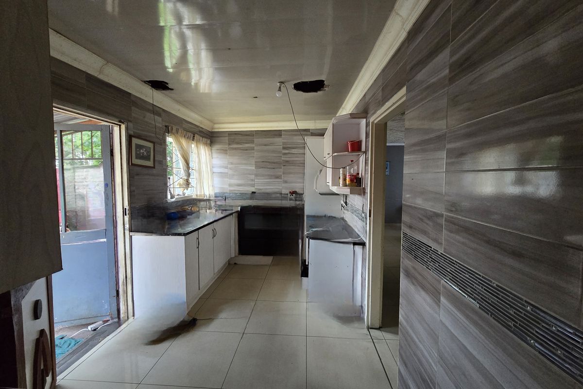 A kitchen space featuring tiled walls and floors with built-in cabinetry, currently requiring ceiling repairs and electrical maintenance.
