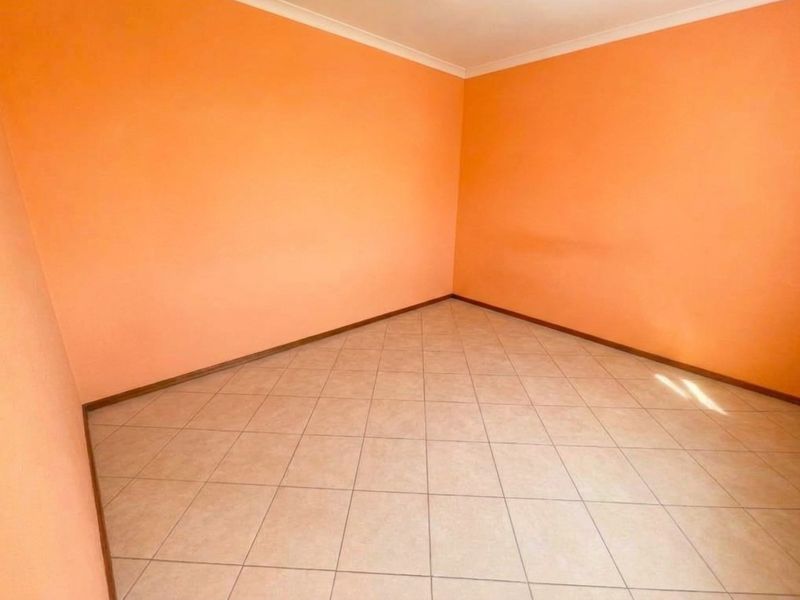 An empty bedroom featuring tiled flooring and orange painted walls, providing a blank canvas for potential interior design updates.
