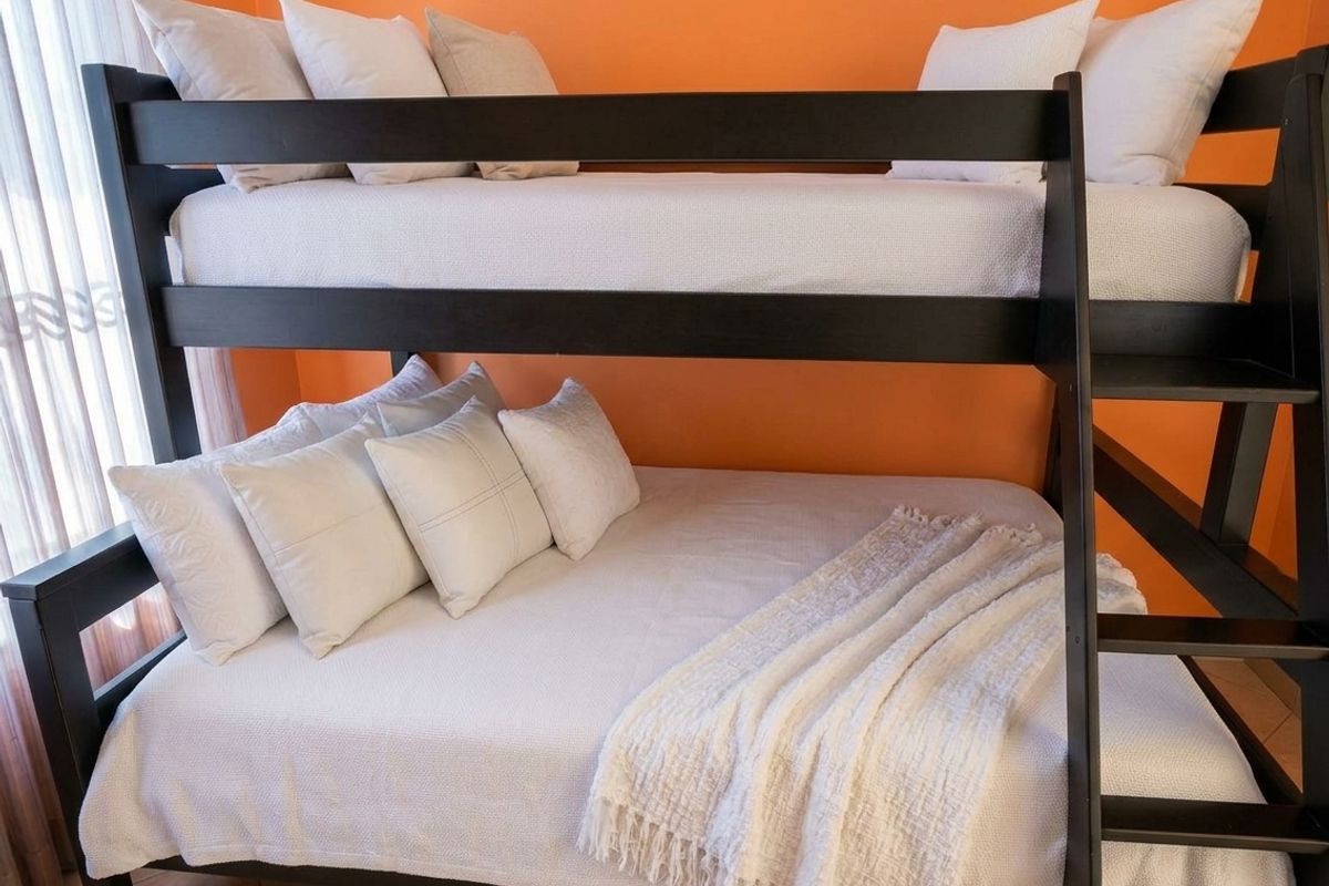 A bedroom featuring tiled flooring and bright orange wall paint, currently furnished with a dark wood bunk bed.
