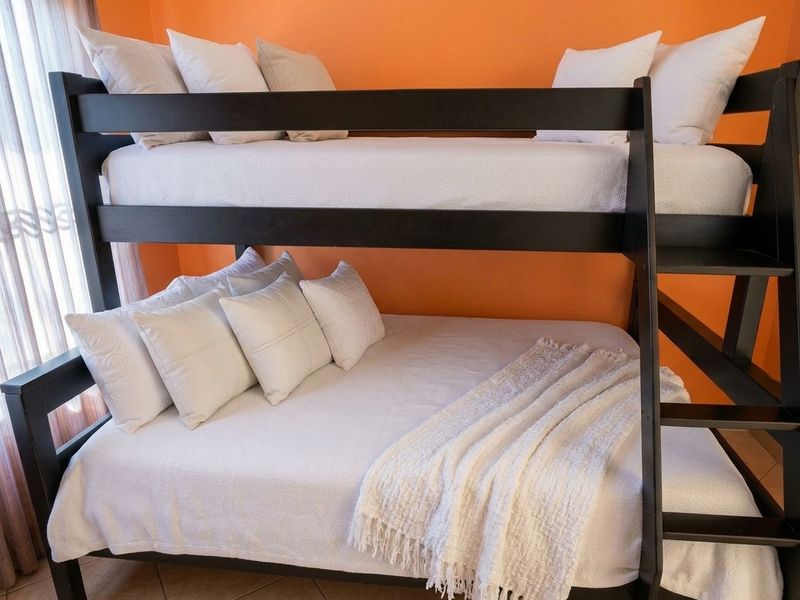 A bedroom featuring tiled flooring and bright orange wall paint, currently furnished with a dark wood bunk bed.