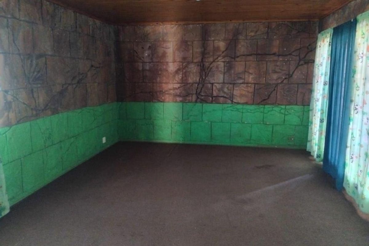 An empty bedroom featuring a timber ceiling and carpeted flooring, currently finished with decorative wall treatments.