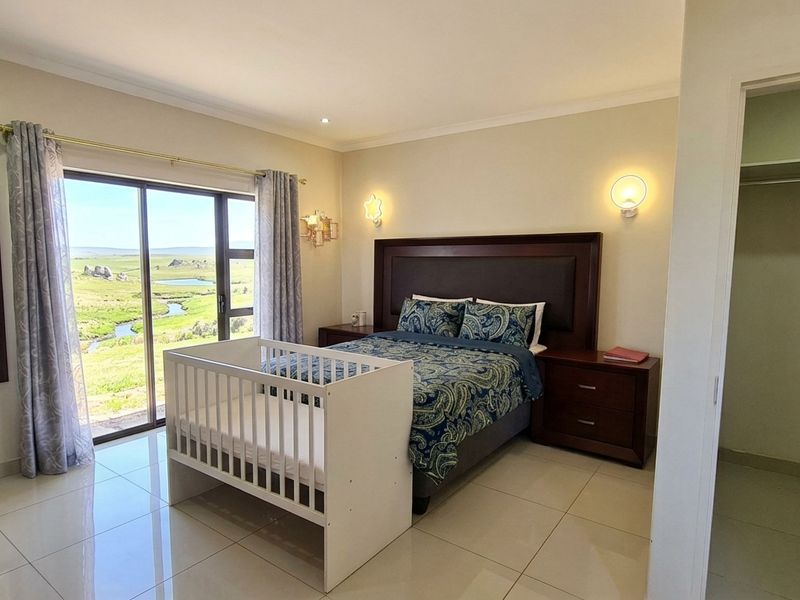 Spacious bedroom featuring tiled flooring, built-in wardrobe, and large sliding glass doors offering scenic landscape views.