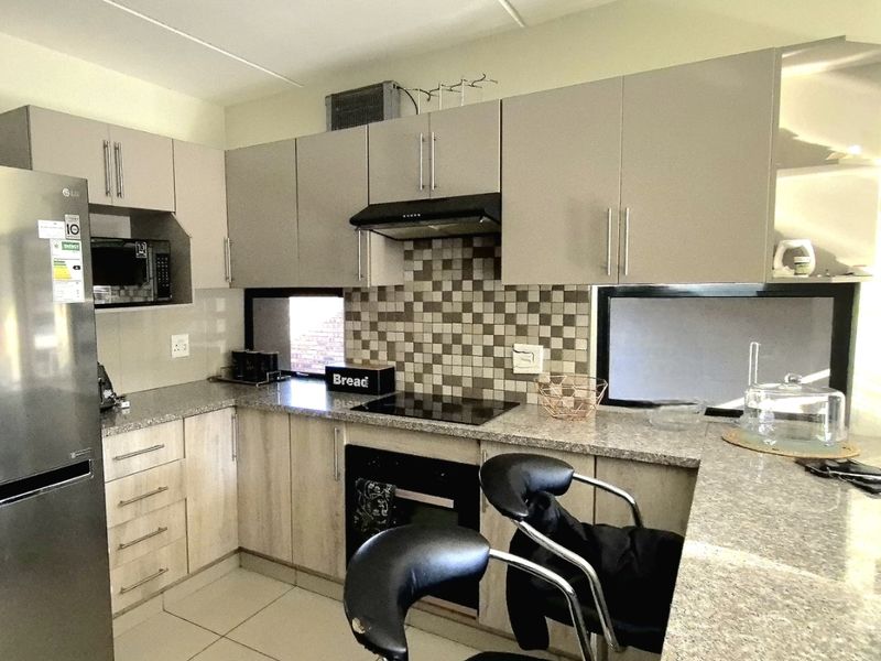 Modern kitchen featuring neutral cabinetry, granite countertops, mosaic tile backsplash, and a convenient breakfast nook for casual dining.
