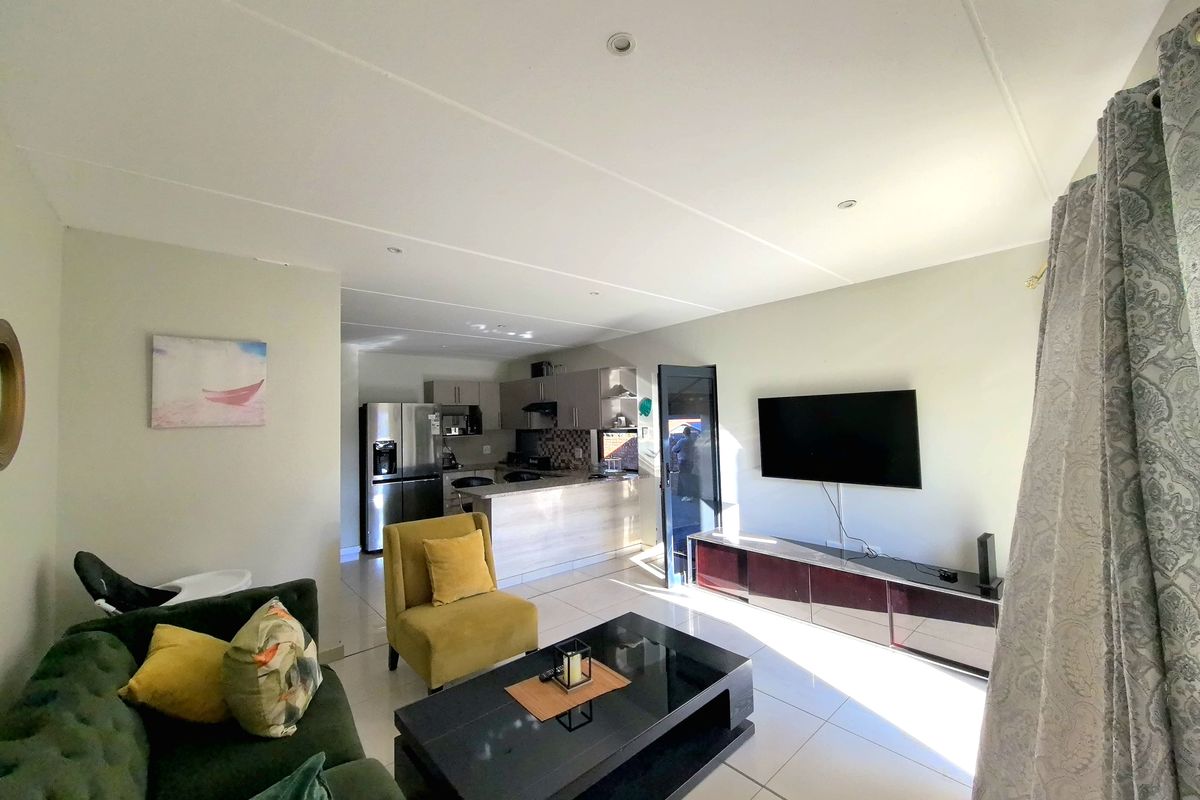 An open-plan living area featuring tiled flooring, recessed lighting, and a functional kitchen with a breakfast bar and modern cabinetry.