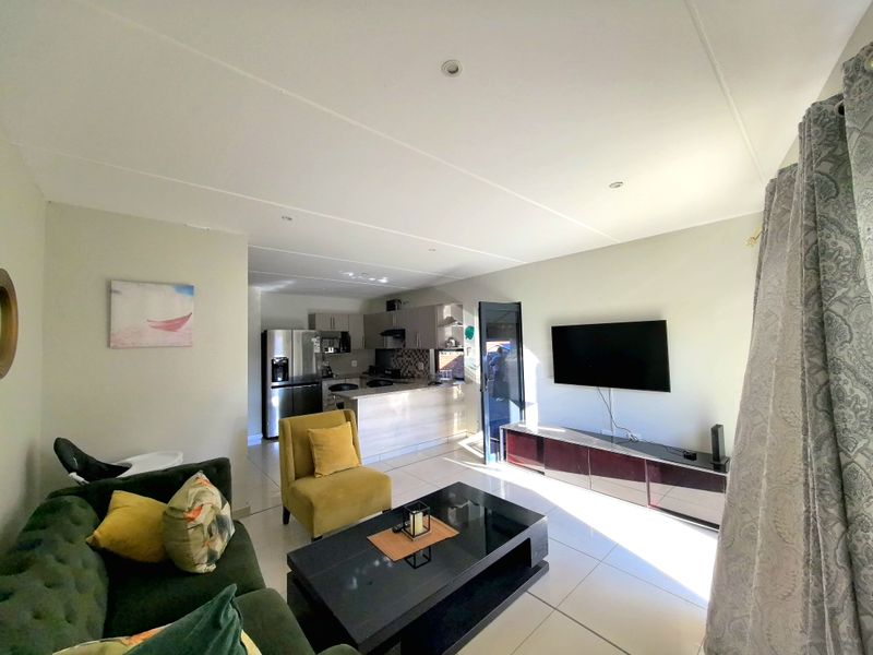 An open-plan living area featuring tiled flooring, recessed lighting, and a functional kitchen with a breakfast bar and modern cabinetry.