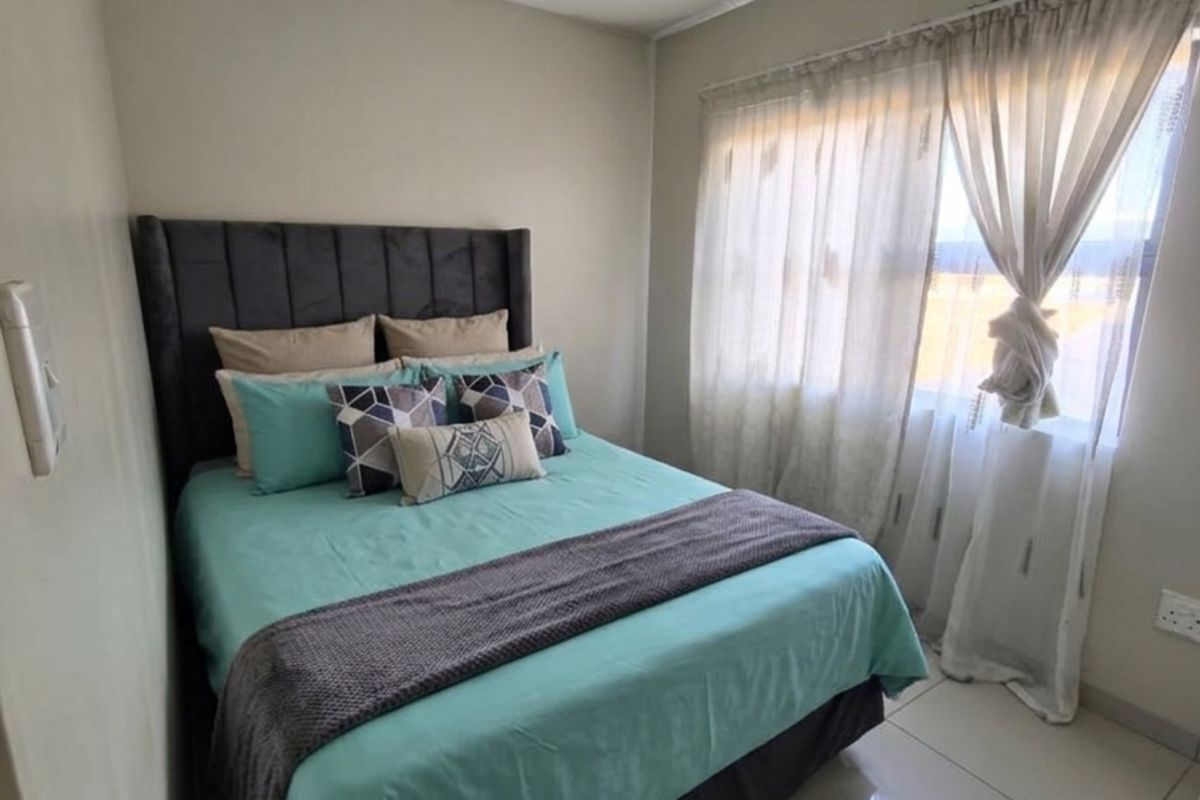 A well-maintained bedroom featuring neutral wall tones, polished tile flooring, and recessed ceiling lighting, providing a clean and functional living space.