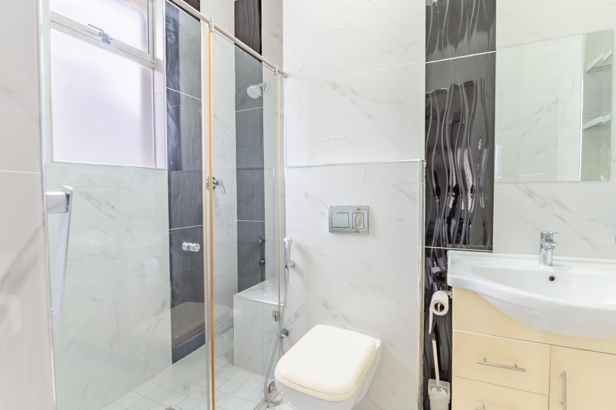 Modern bathroom featuring a glass-enclosed shower with a built-in bench, wall-mounted toilet, and a vanity cabinet with a ceramic basin.